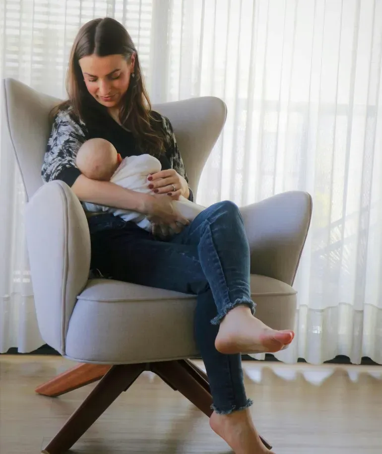 Madre amamantando a su bebé en una silla en su casa